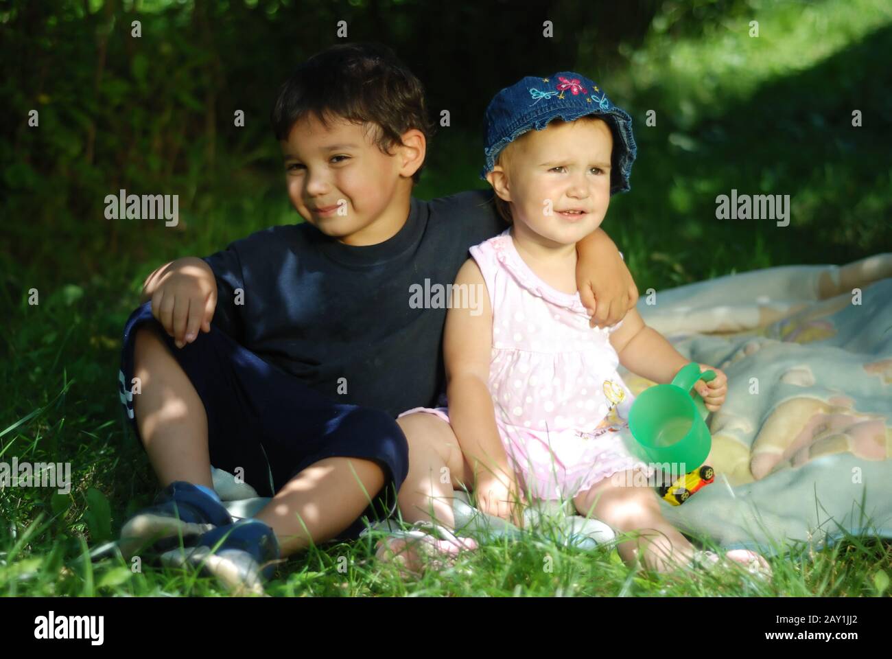 Two children sitting and playing on the grass Stock Photo - Alamy