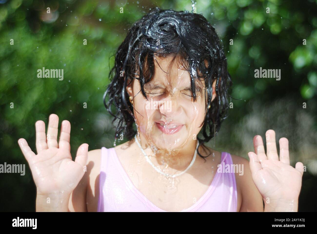 Little girl splashing with water in hot summertime Stock Photo