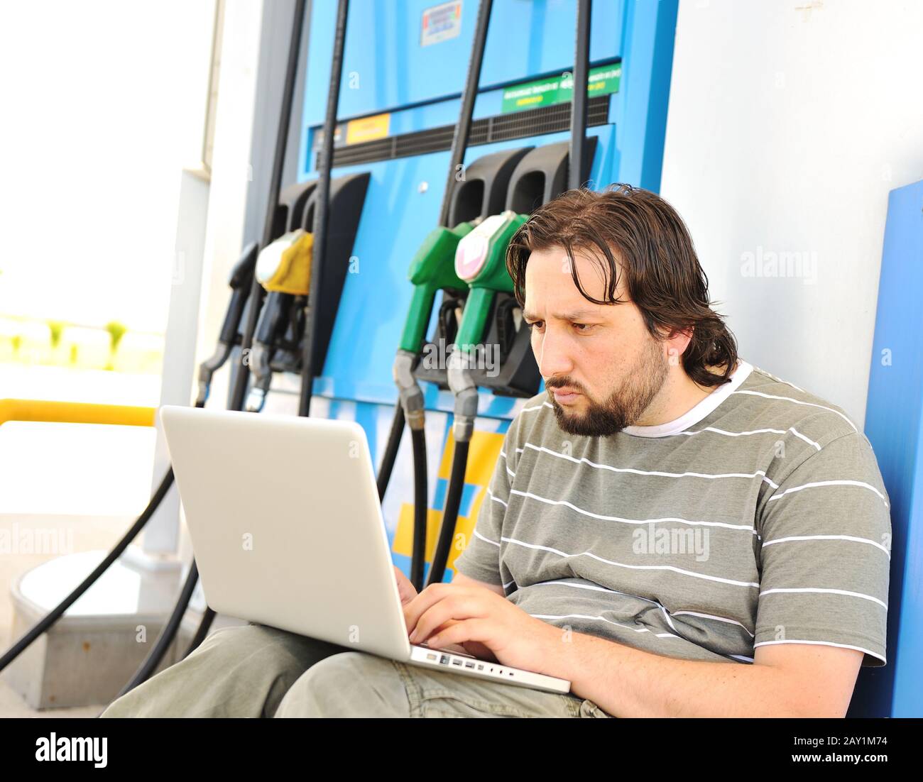A man with worried face with laptop on fuel station Stock Photo