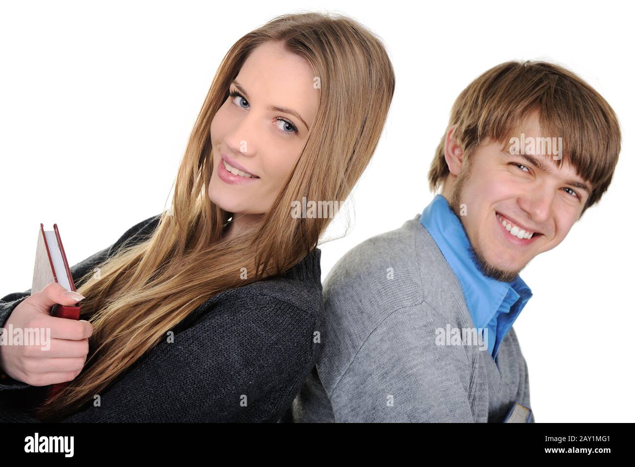 Portrait of a happy young teenage boy and girl standing back to back ...