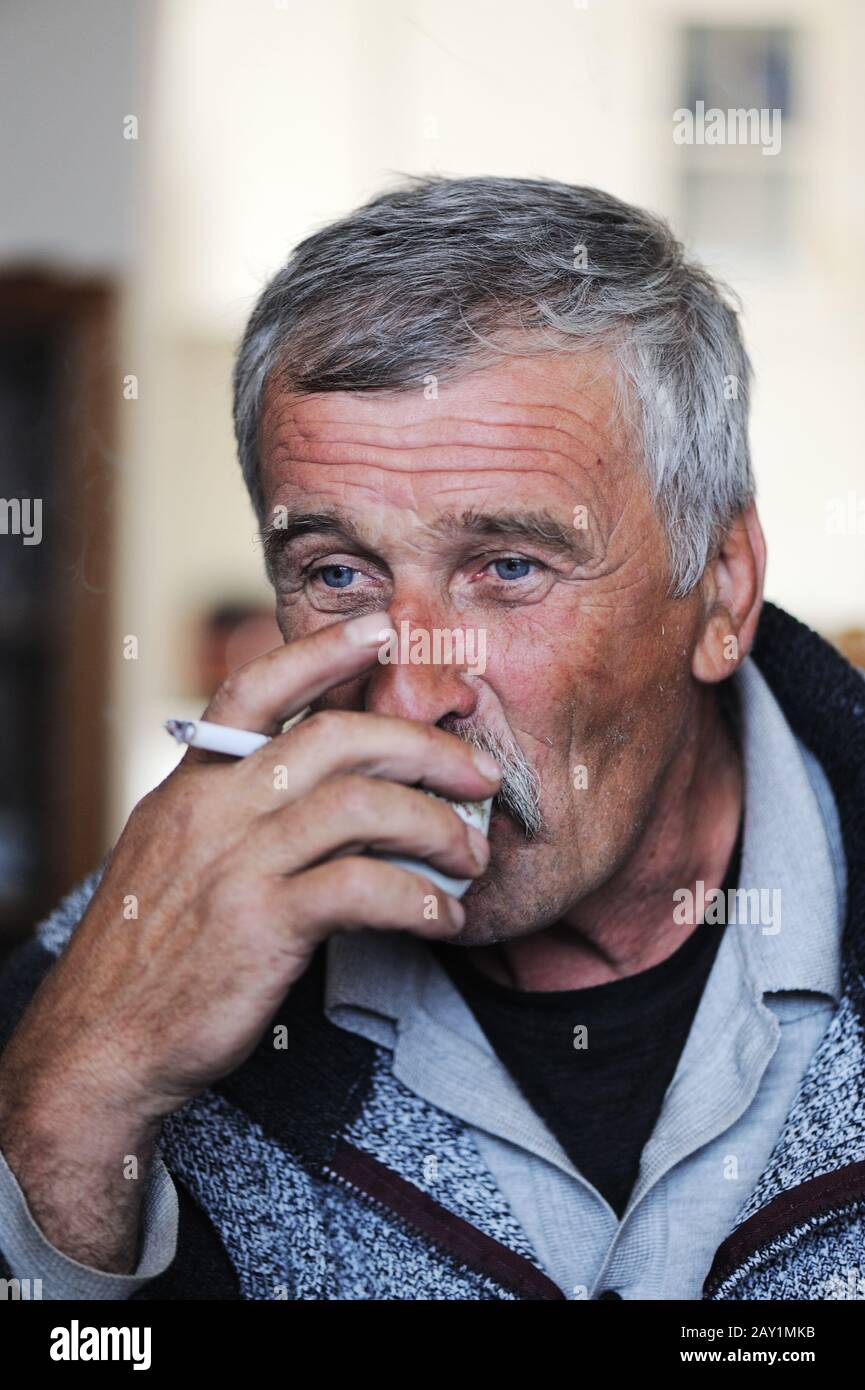 Old man with mustache smoking cigarette and drinking coffee Stock Photo