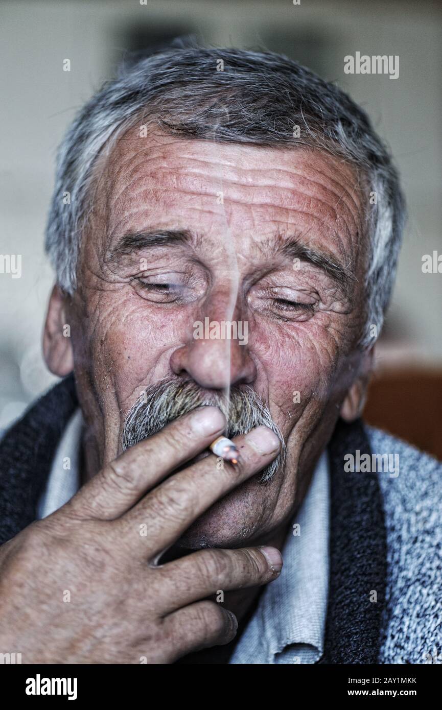 Common elderly man with mustache smoking cigarette Stock Photo