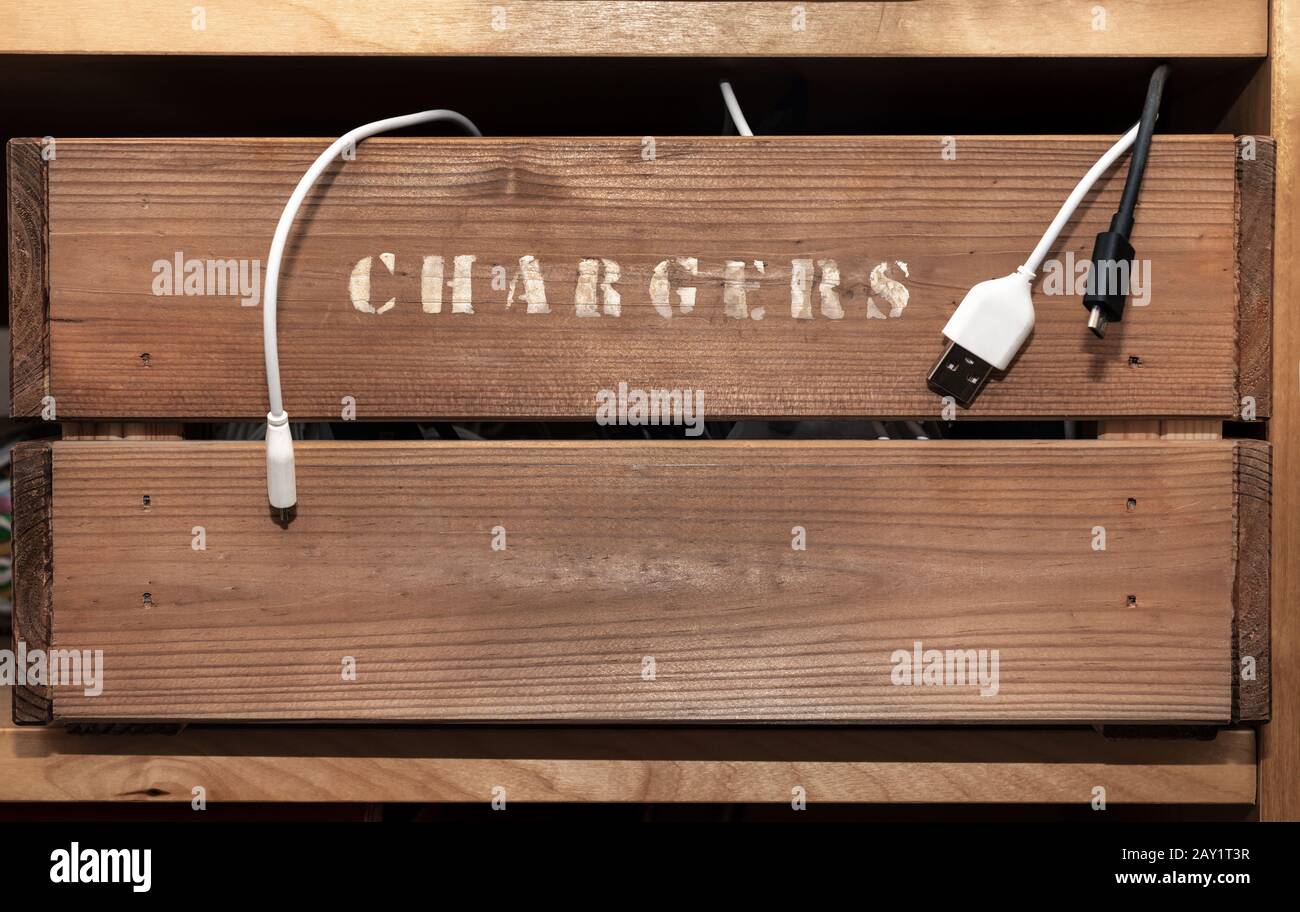 An old vintage style crate on a shelf with the word chargers hand painted on the side. Cables hang out over the edge. Stock Photo