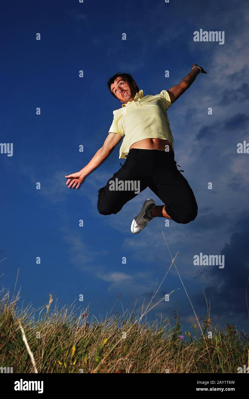Young happy man is jumping on green meadow Stock Photo