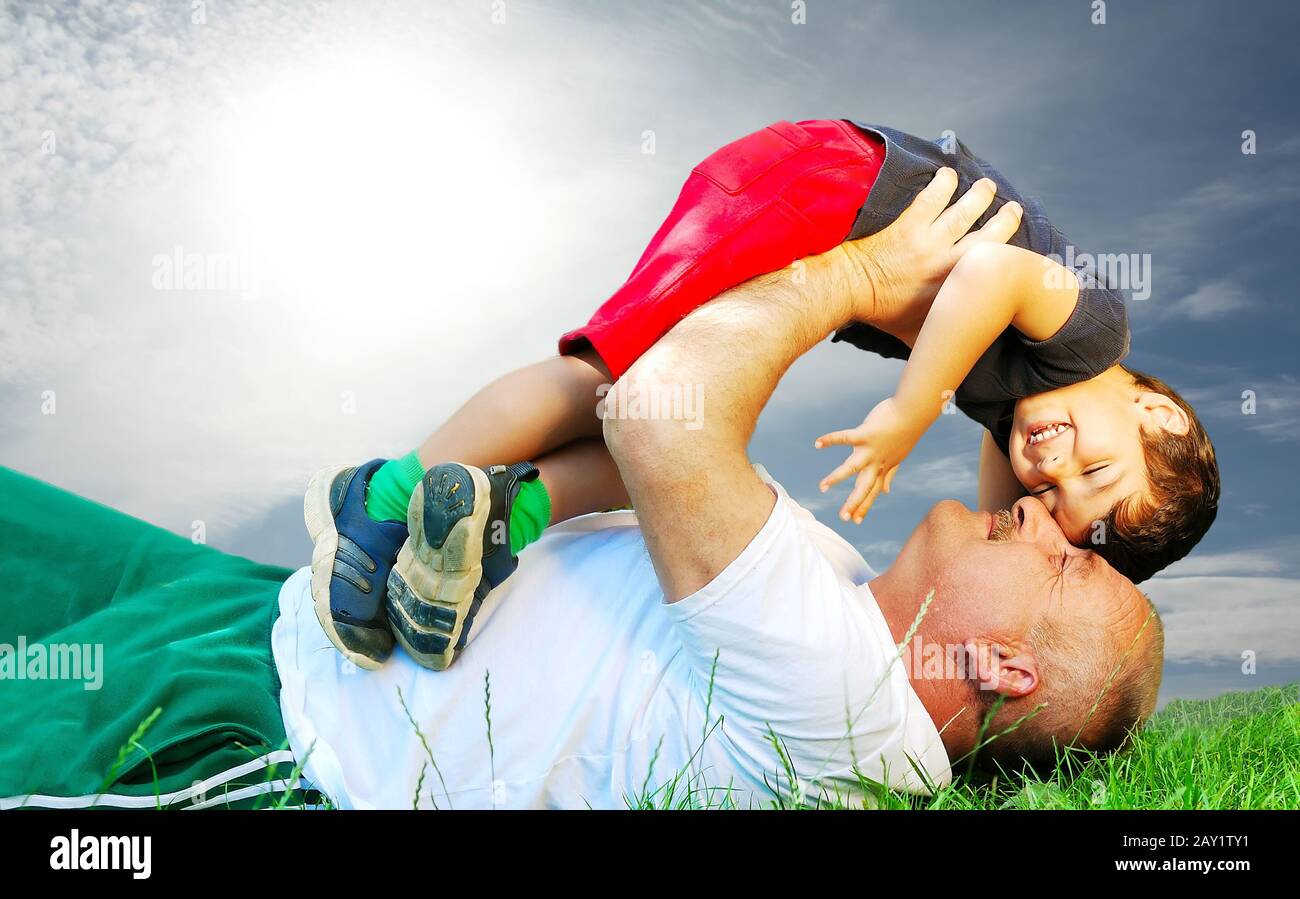 A parent and his kid laying and smiling on grass Stock Photo
