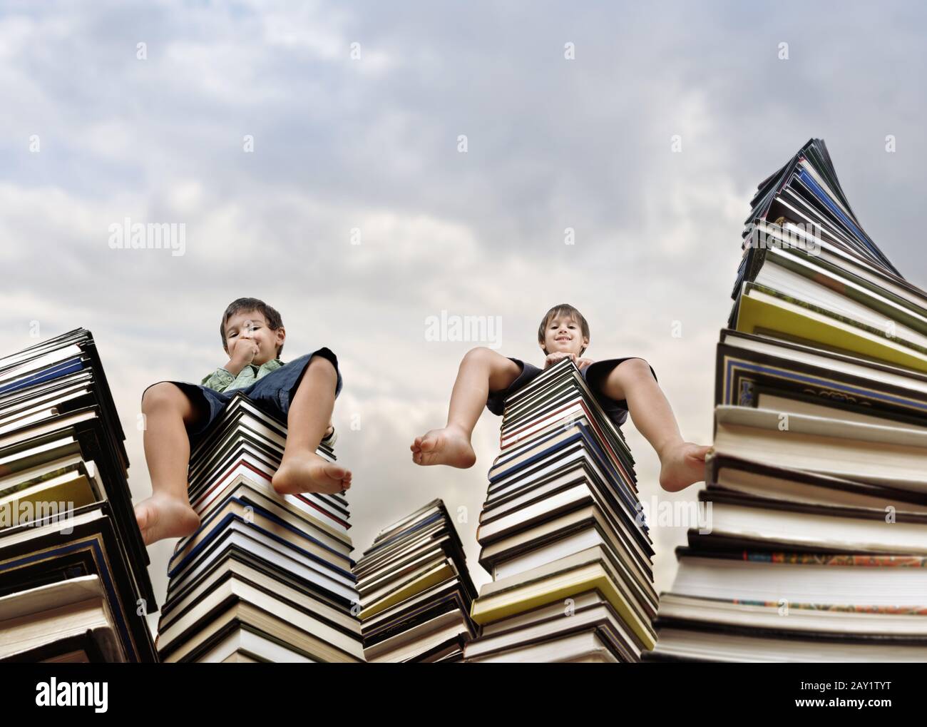 Little boy sitting on large stack of books Stock Photo - Alamy