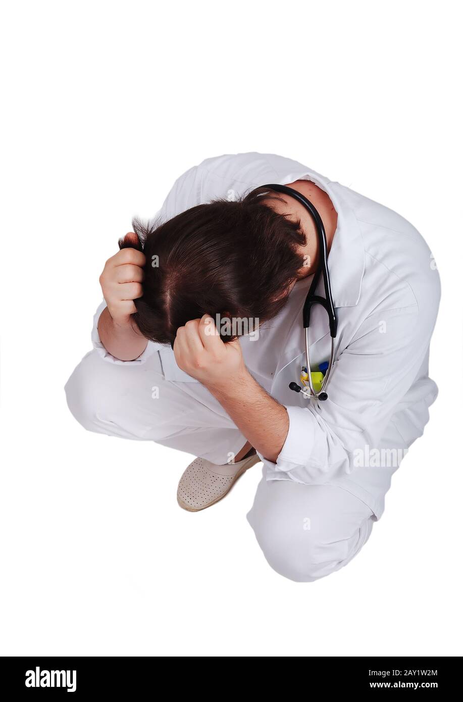 Young male doctor sitting down with hands on his head Stock Photo
