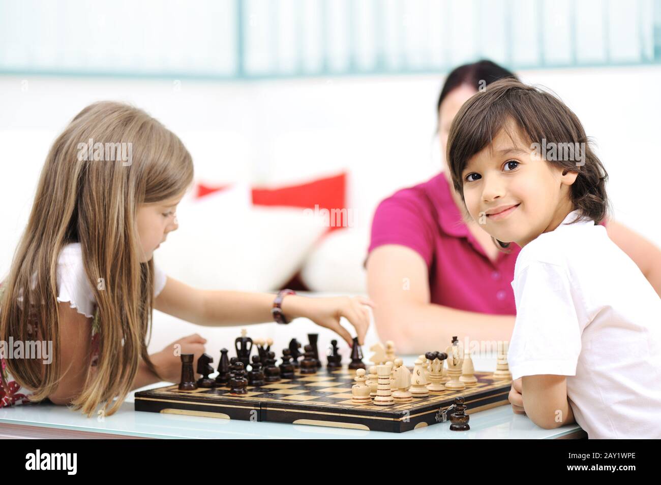 Brother and sister playing chess at home with their mother Stock Photo Alamy
