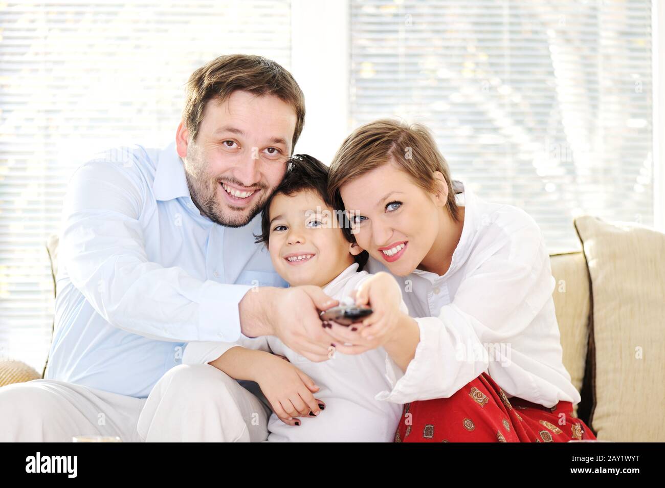 Family sitting in living room with remote control Stock Photo