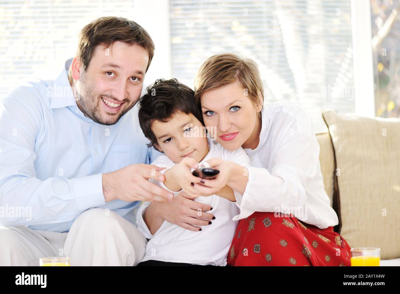 Family sitting in living room with remote control Stock Photo