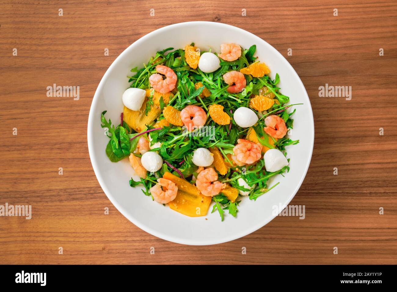 Vegetarian salad with arugula, persimmon, mandarine, shrimps and mozzarella Stock Photo