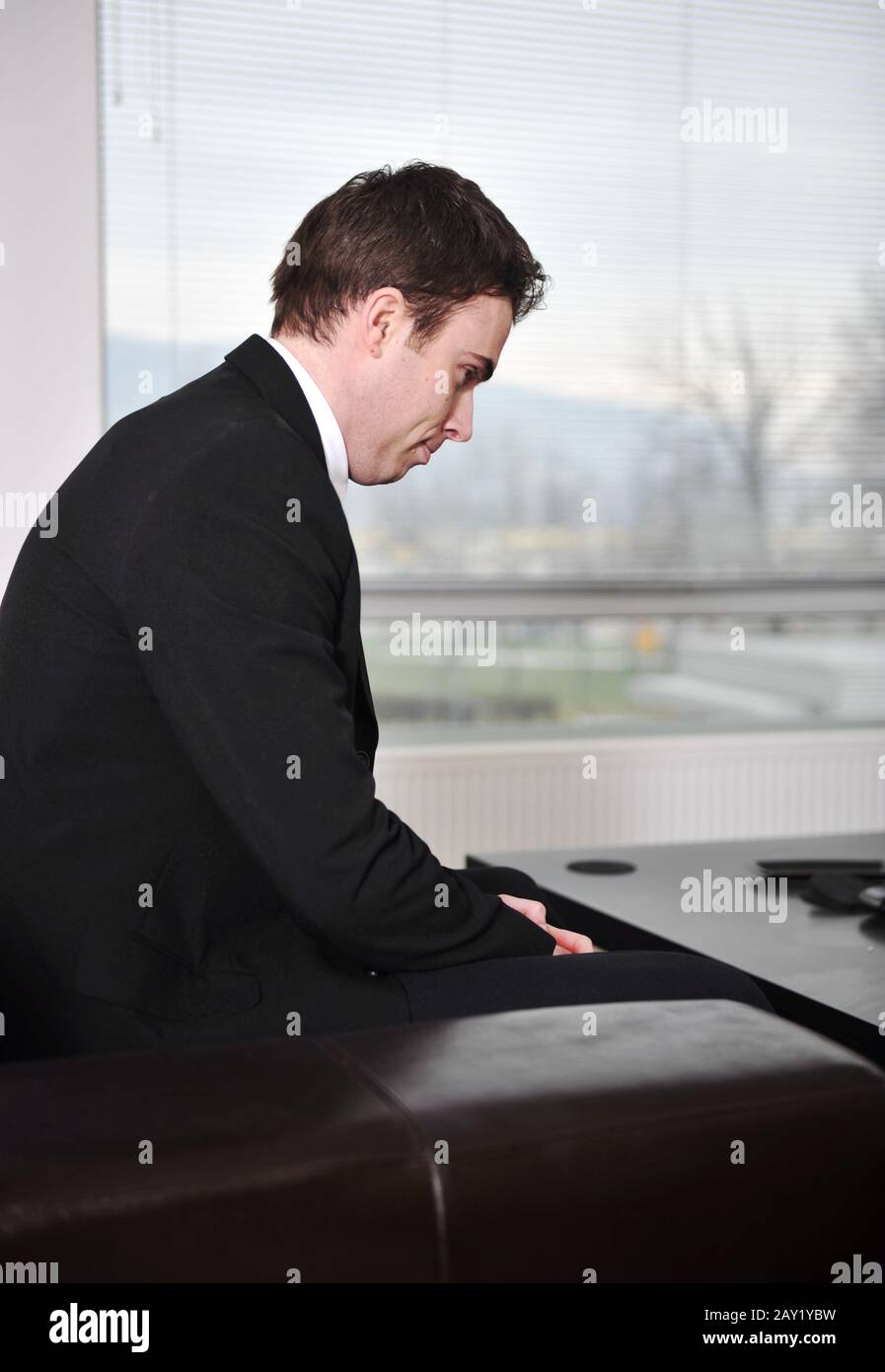 Young businessman sitting on sofa at office lobby Stock Photo