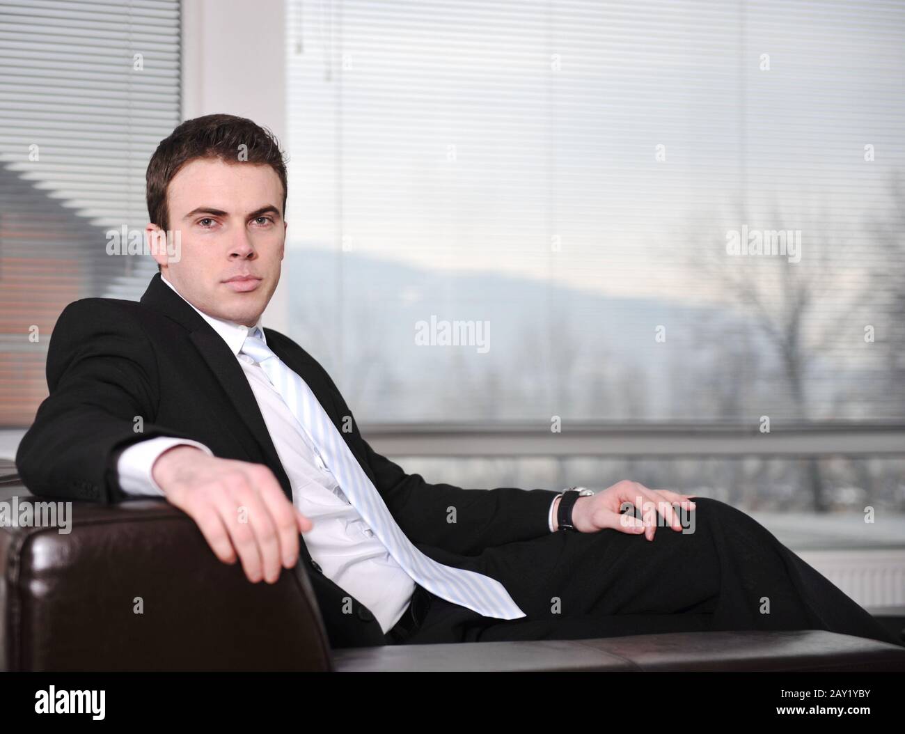 Businessman sitting on leather sofa in office Stock Photo