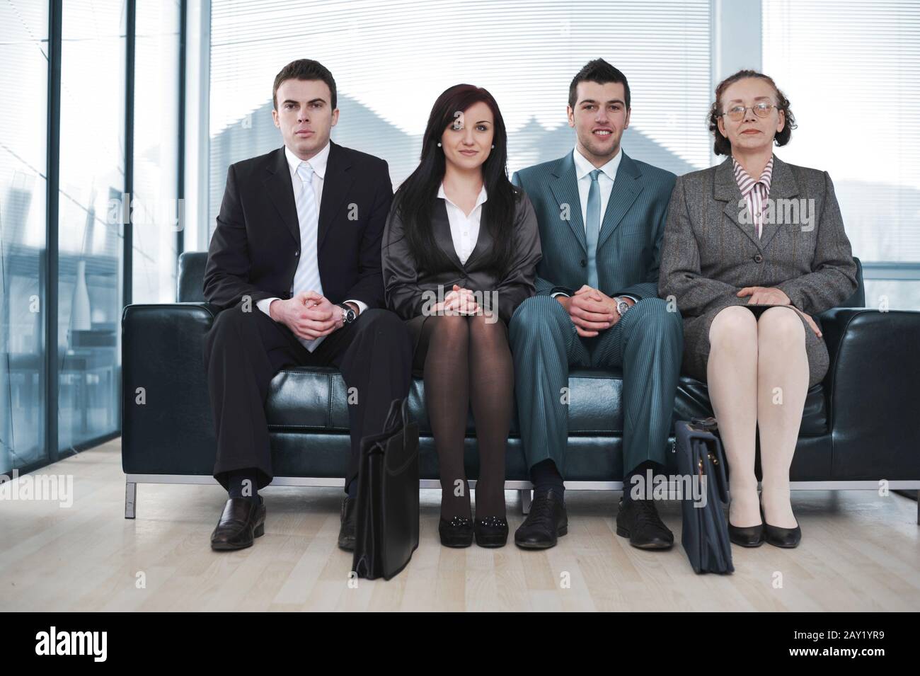 Four business people sitting in a row on sofa Stock Photo