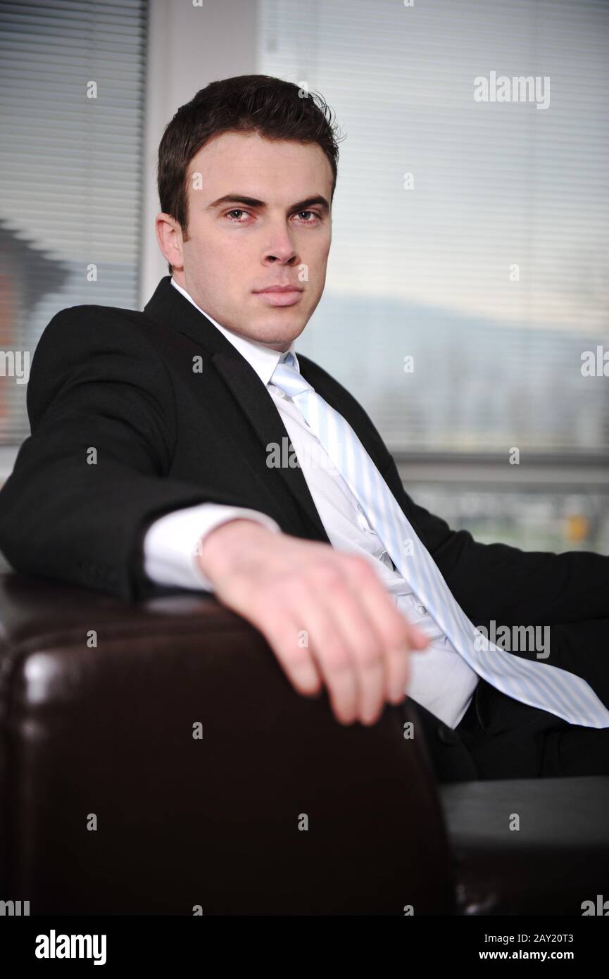 Businessman sitting on sofa in modern office Stock Photo