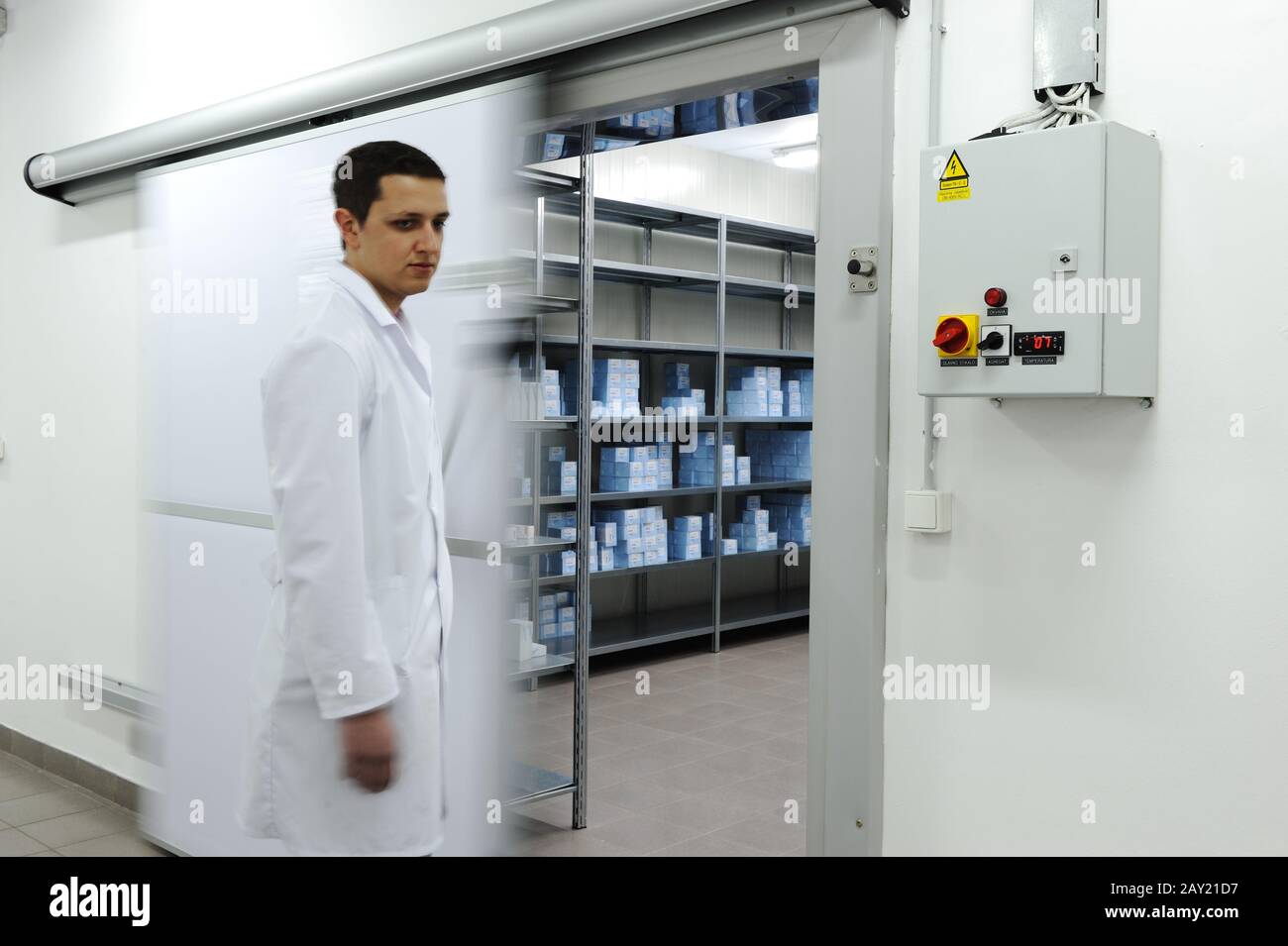Young worker opening  door of industrial refrigerator Stock Photo