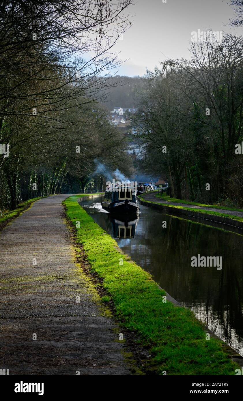 Narrowboat, with smoke coming from its chimney, makes its way toward the Pontcysyllte Aqueduct on the Llangollen canal on a cold winters day. Stock Photo