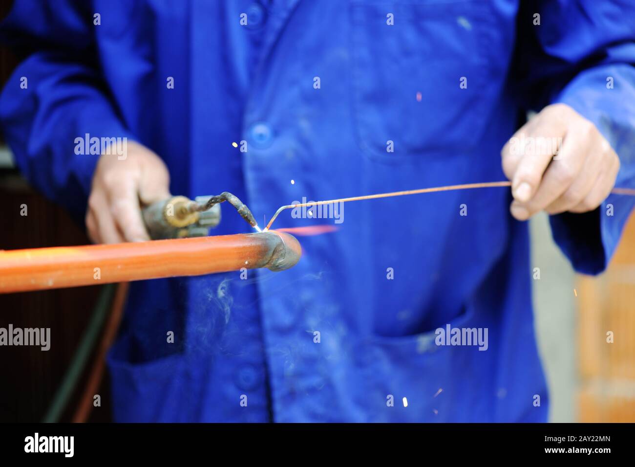 Worker in blue suit welding metal Stock Photo