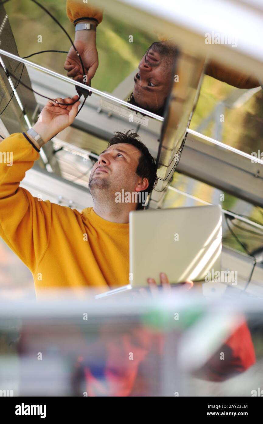 Engineer using laptop and connecting wires at work place Stock Photo