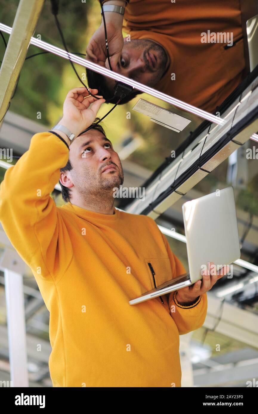Engineer using laptop and connecting wires at work place Stock Photo