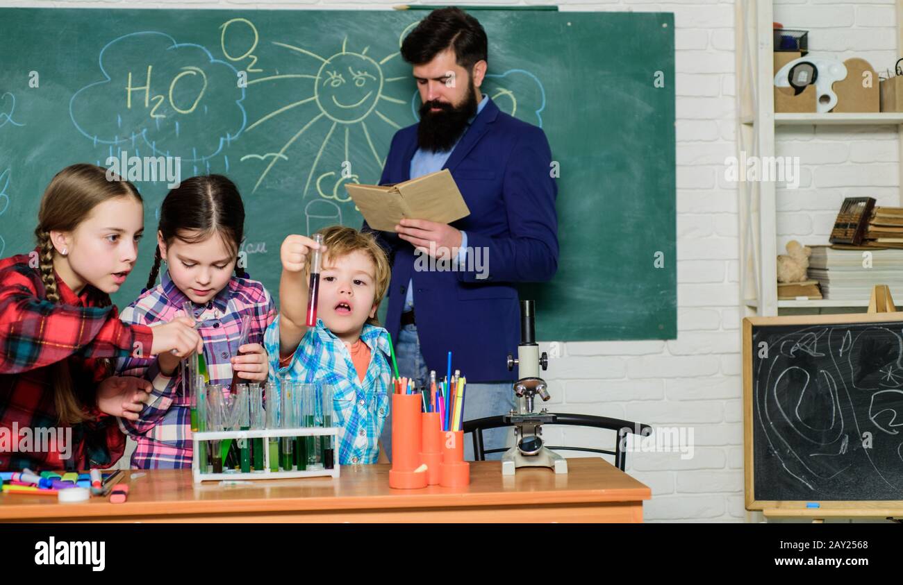 happy children teacher. doing experiments with liquids in chemistry lab. chemistry lab. back to school. kids in lab coat learning chemistry in school laboratory. they need an expert advice. Stock Photo