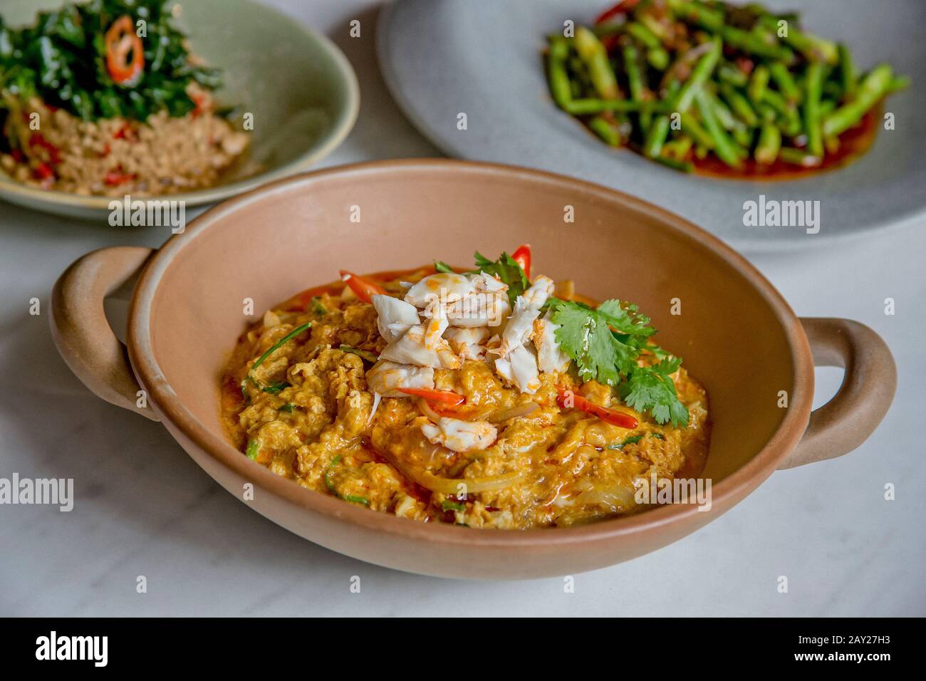 Thai food is  characterized by lightly prepared dishes with strong aromatic components and a spicy edge. Here is a crab curry, long beans and pork. Stock Photo