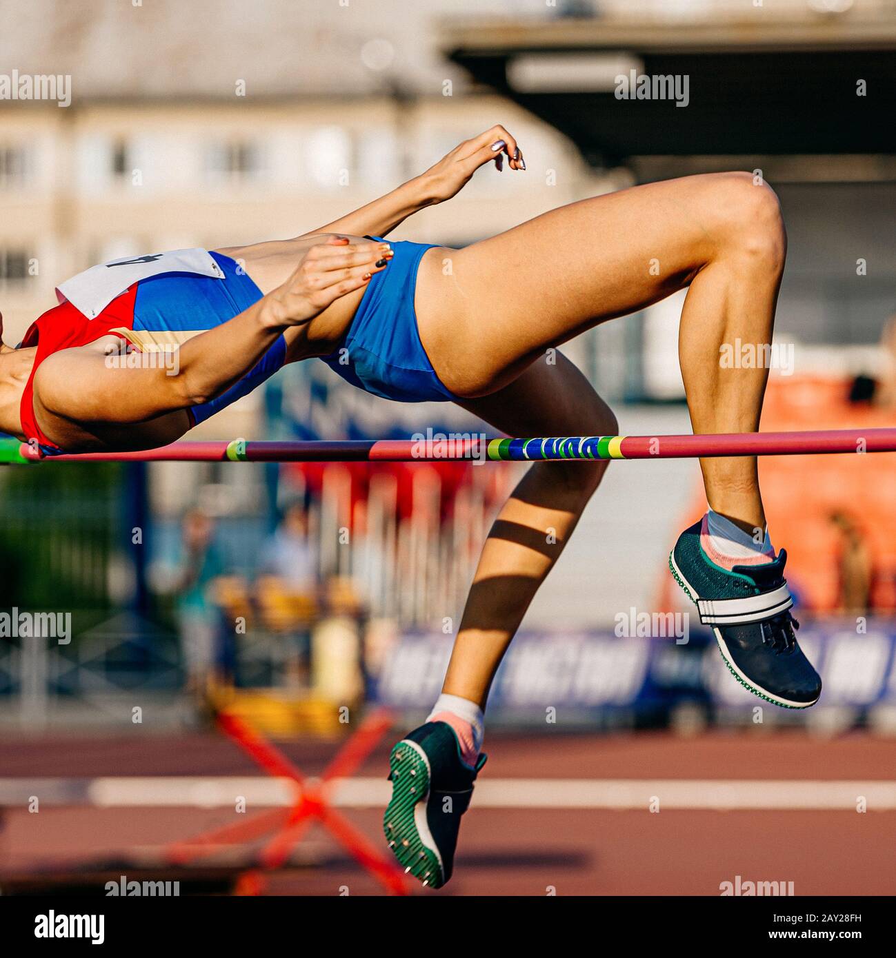women athlete jumping high jump in athletics competition Stock Photo