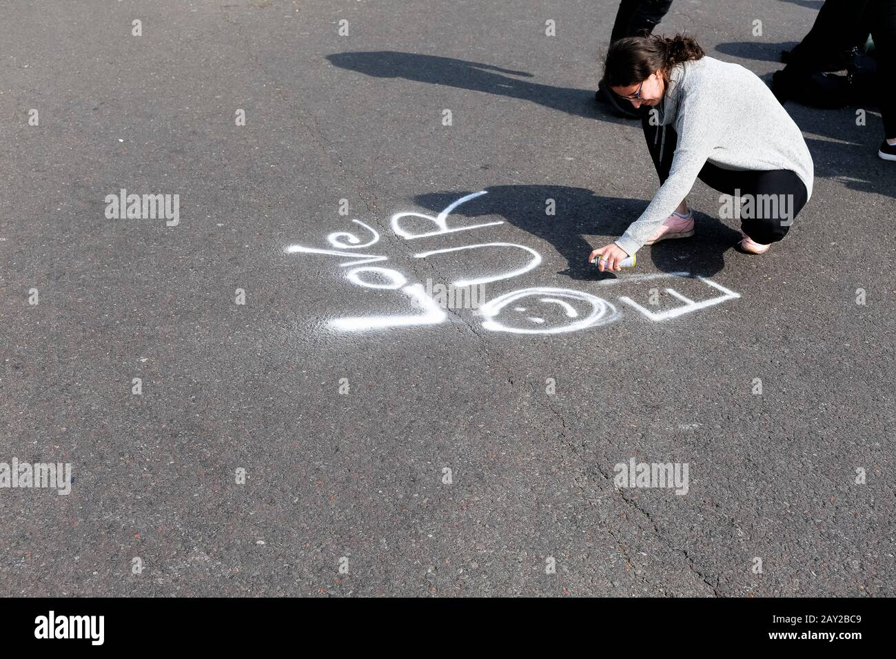 London, UK. A female protester uses white spray paint in the middle of the road as London comes to a standstill as protesters with the Extinction Rebe Stock Photo