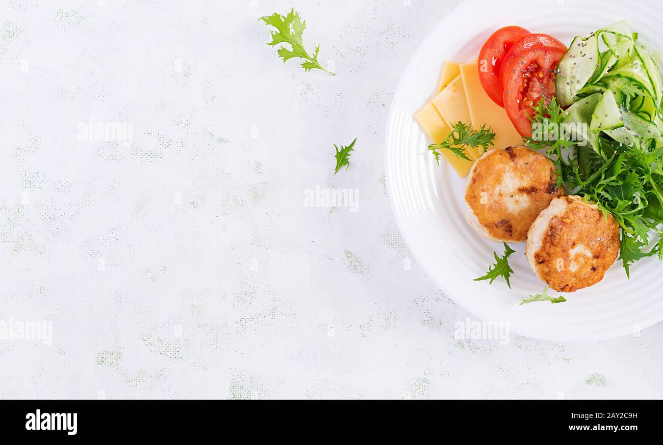 Ketogenic lunch. Chicken burger with tomato, cucumber, cheese and arugula salad without bun