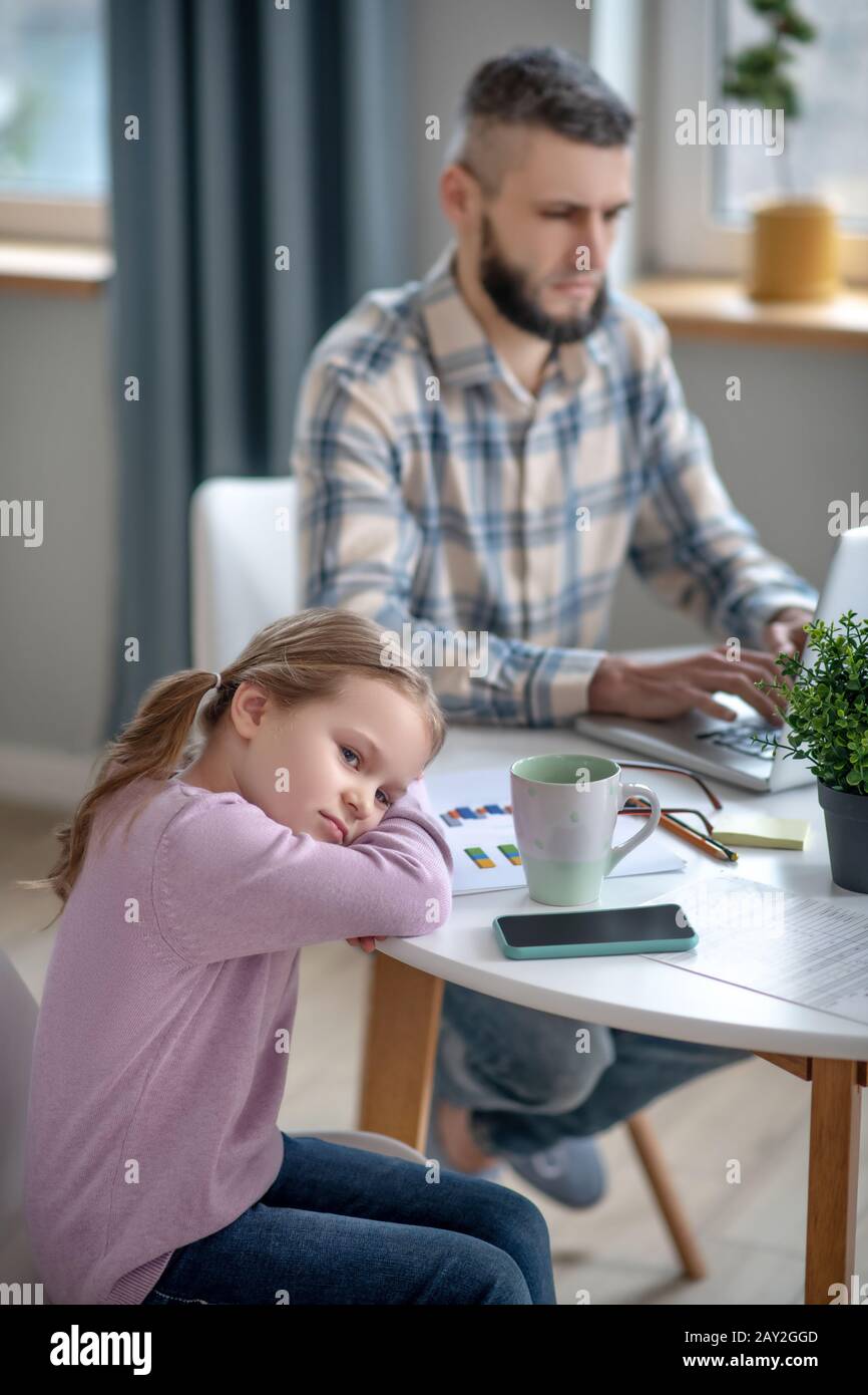 Sad daughter resting her head in her arms, on the table. Stock Photo