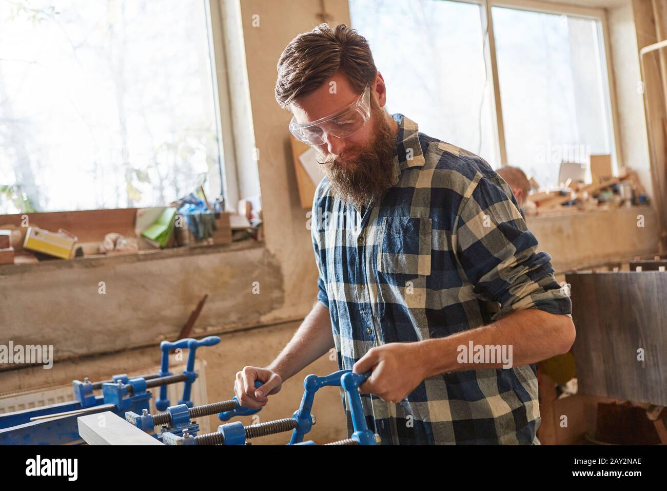 Carpenter with safety glasses as a furniture maker works with wood on a vice Stock Photo