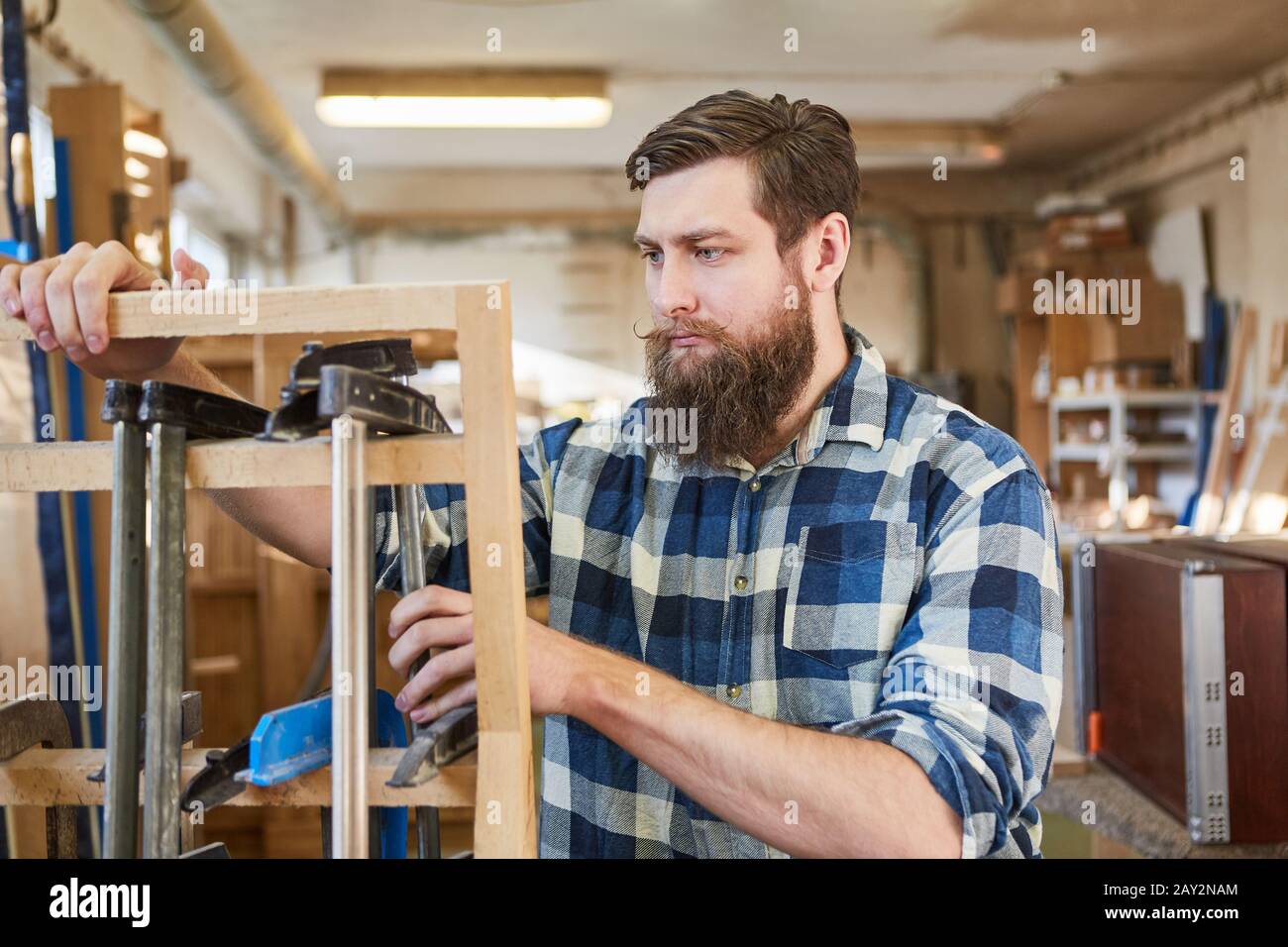 Hipster carpenter sorts screw clamps in the joinery or joinery Stock Photo