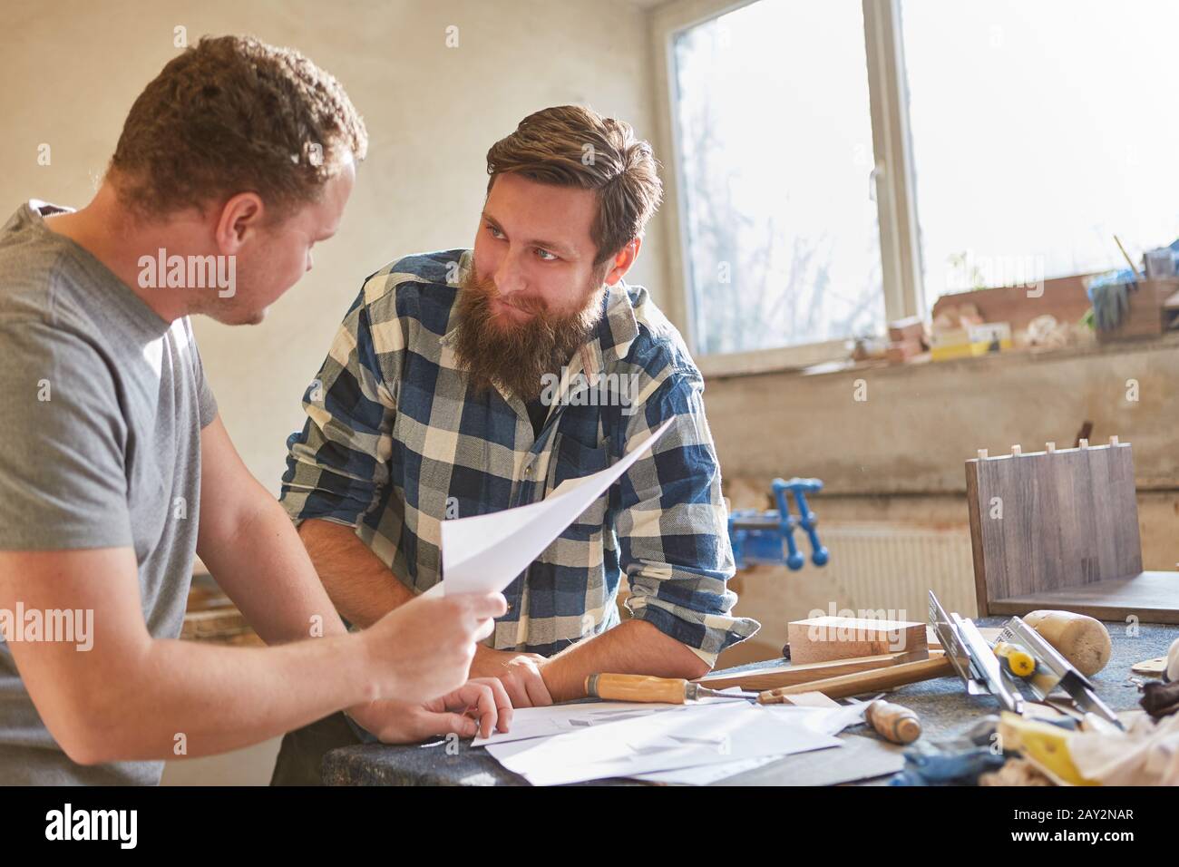 Two carpenters or carpenters discuss an order on a piece of paper Stock Photo