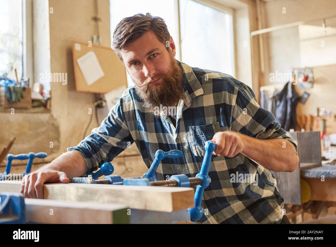 Hipster carpenter as a furniture maker works with a wooden workpiece on a vice Stock Photo