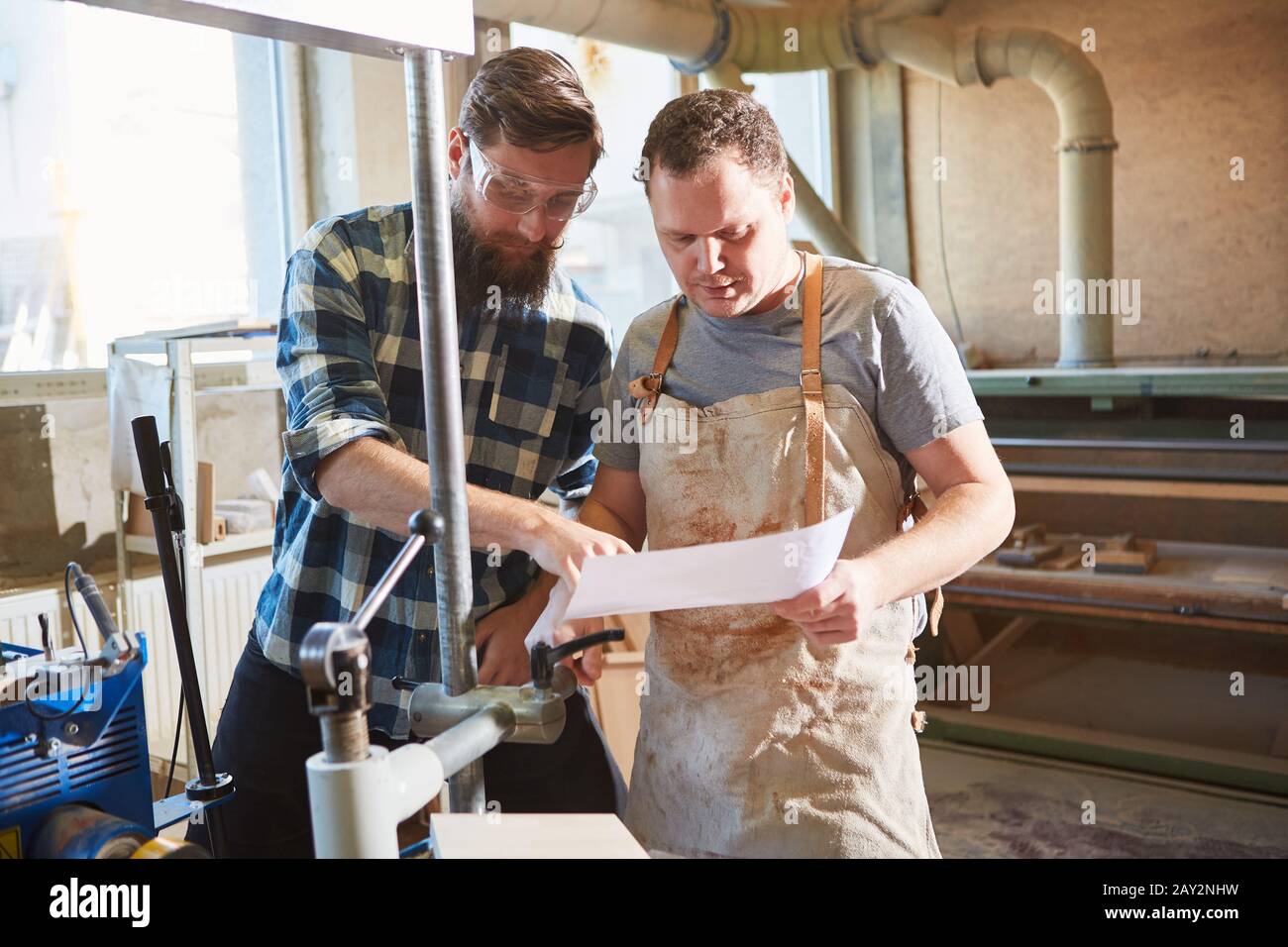 Carpenter apprentice with order on sheet of paper together with instructor Stock Photo
