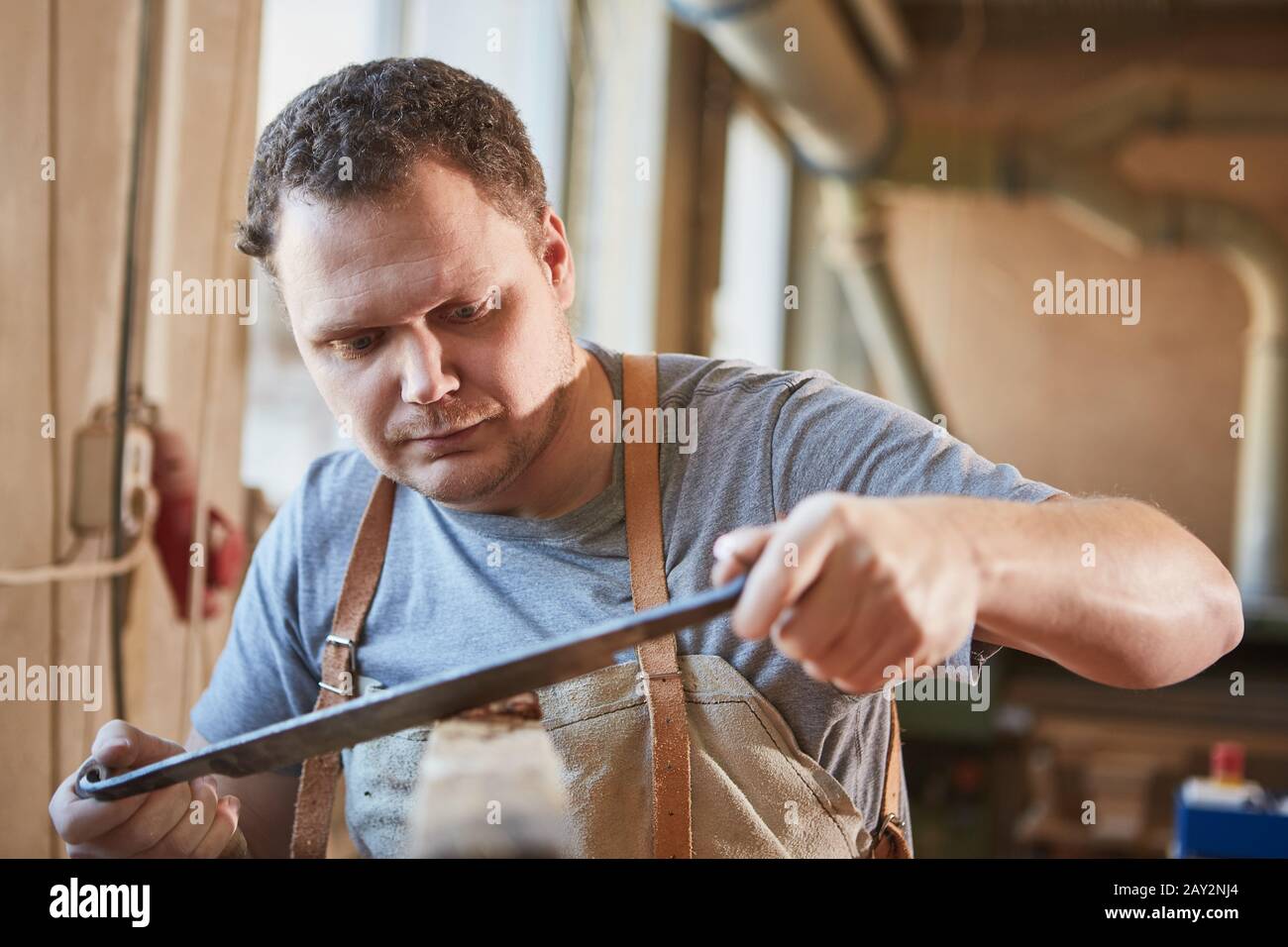 Craftsman apprentice with a tension knife for debarking wood Stock Photo