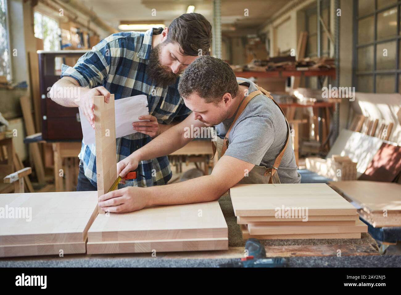 Two furniture builders measuring furniture part for a shelf in the carpentry Stock Photo