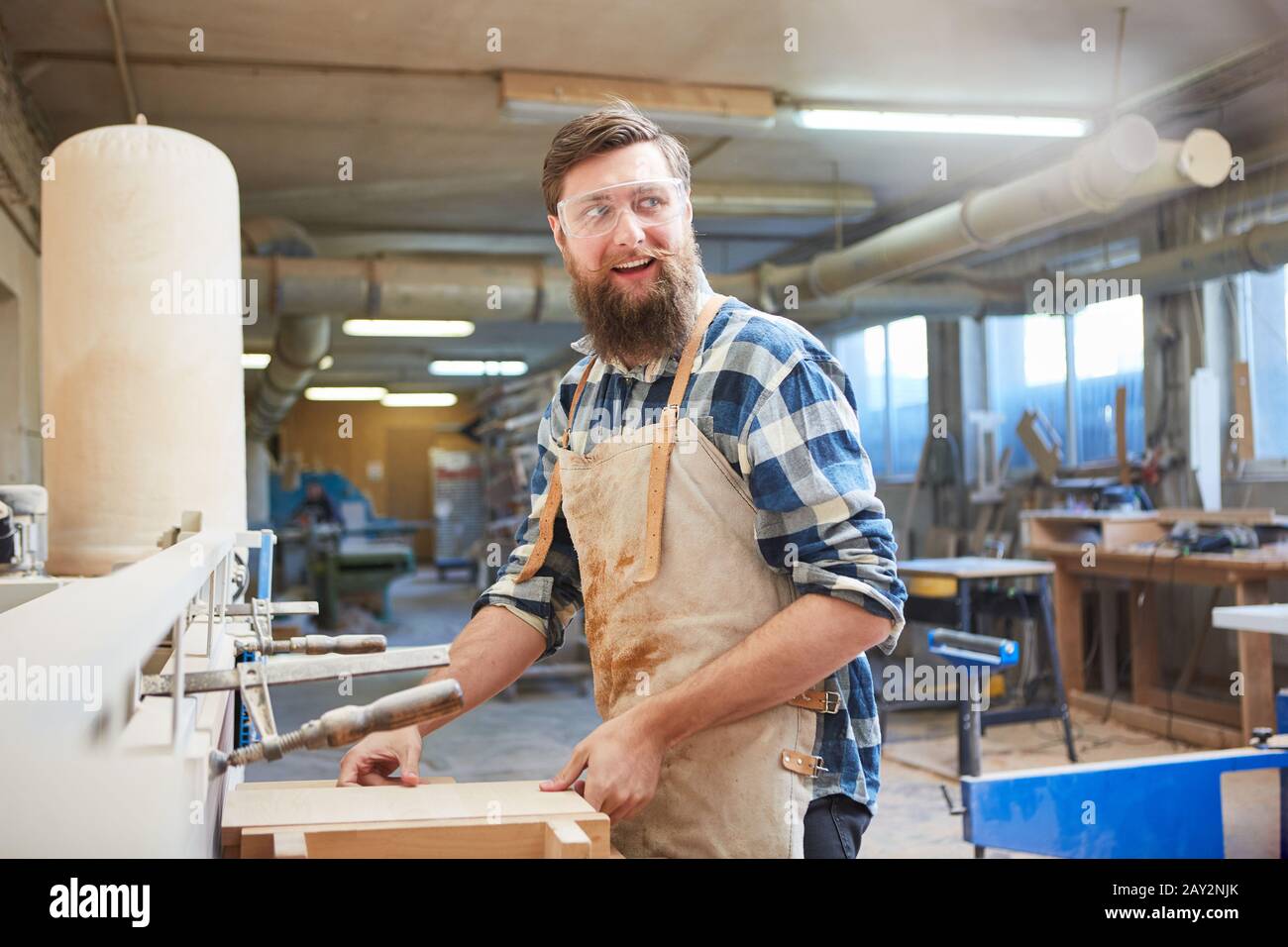 Carpenter apprentice works as a furniture maker with wood on the grinding machine Stock Photo