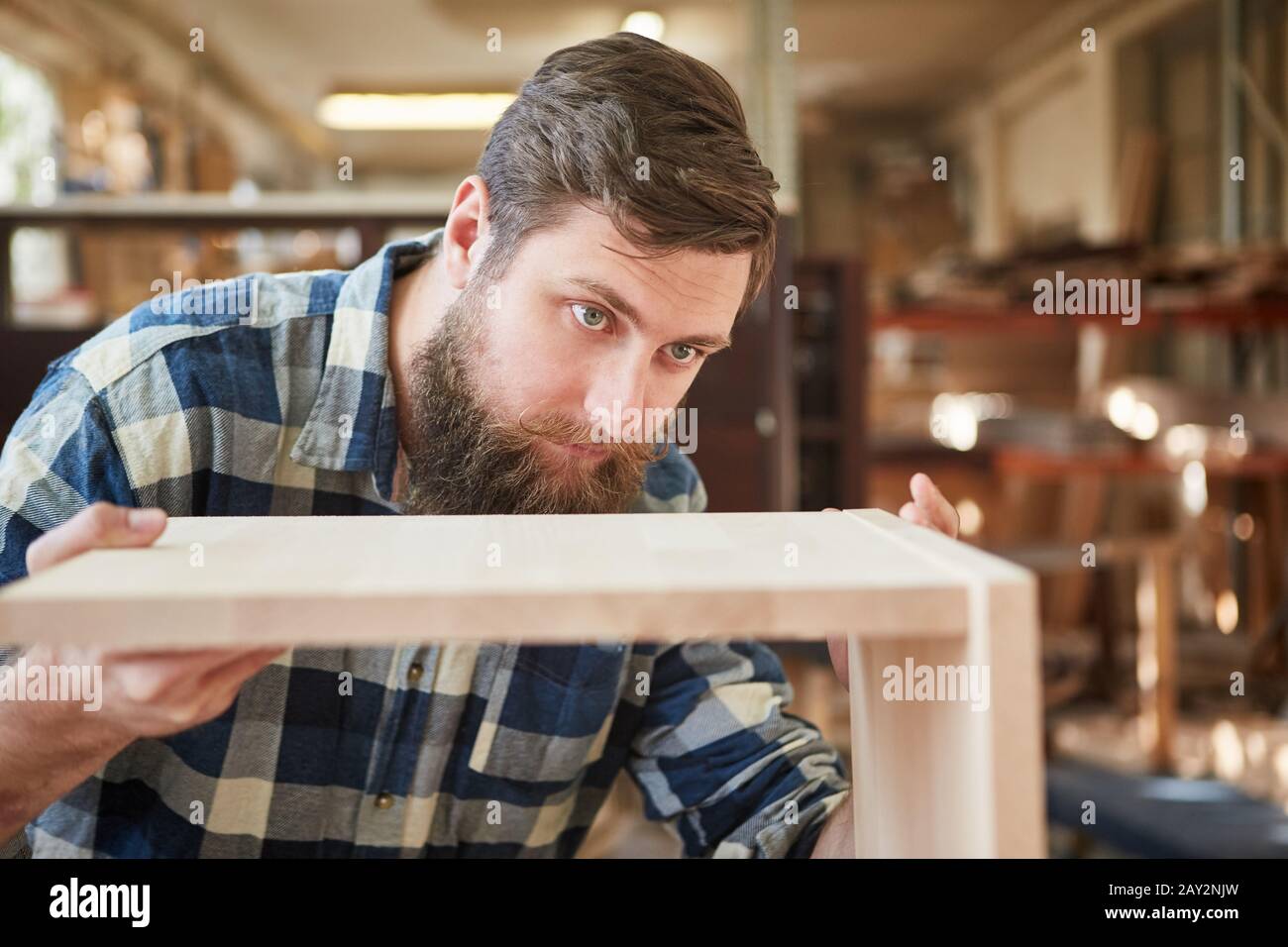 Carpenter in training builds a wooden shelf in a carpentry or joinery shop Stock Photo