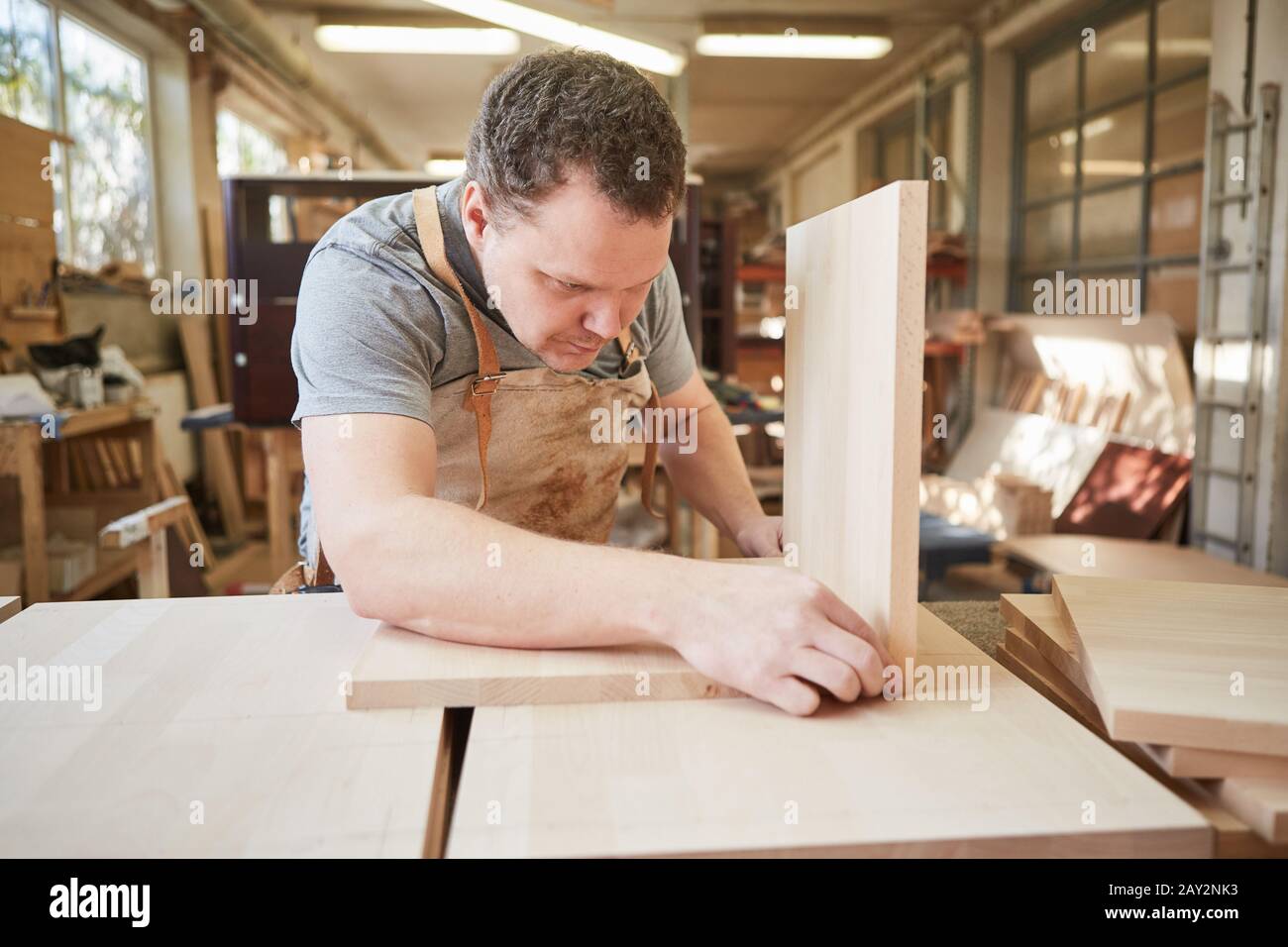 Carpenter trainee as a furniture maker builds a wooden shelf in a joinery Stock Photo