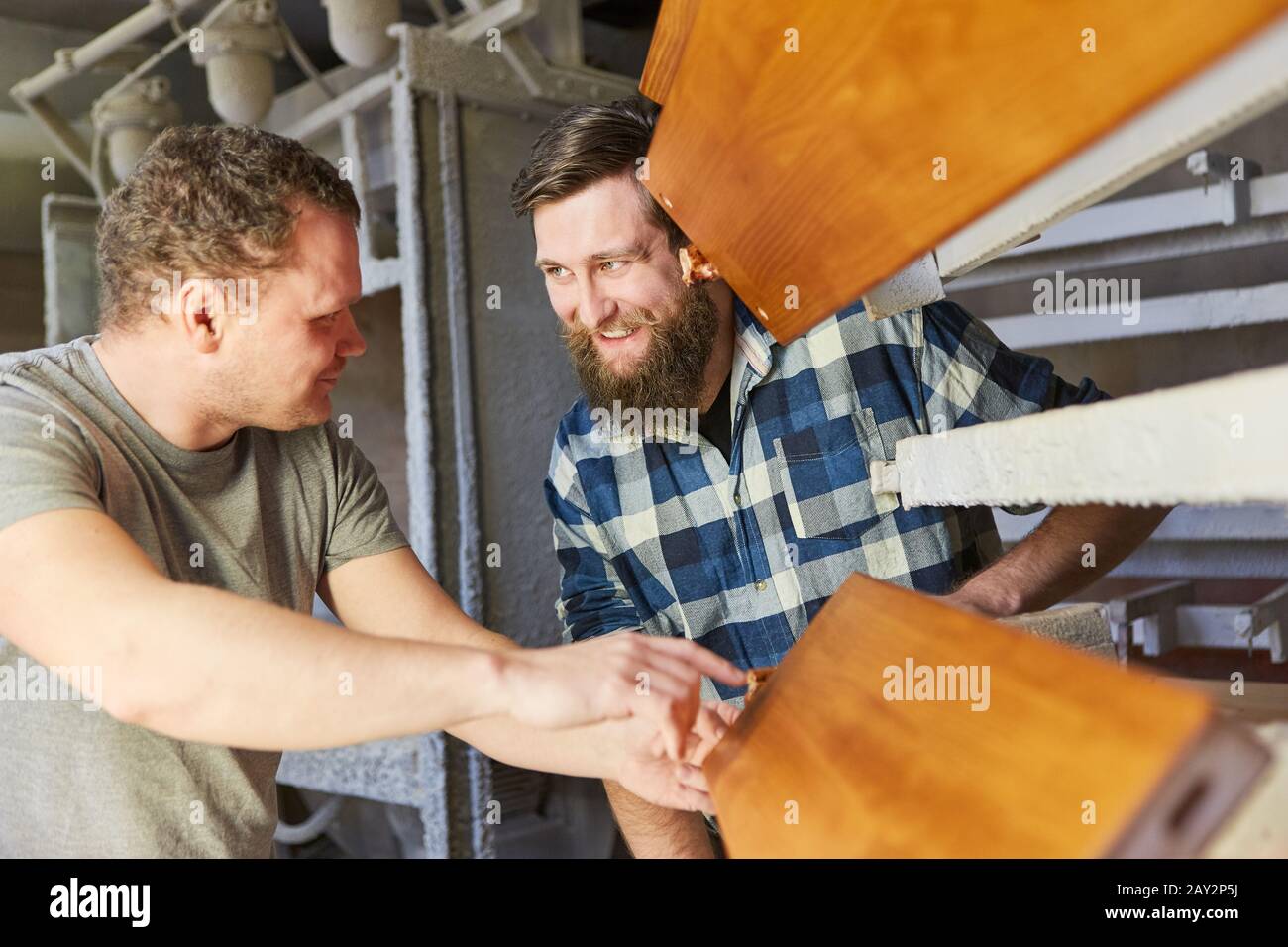 Two carpenters as furniture makers discuss a wooden workpiece in the joinery Stock Photo