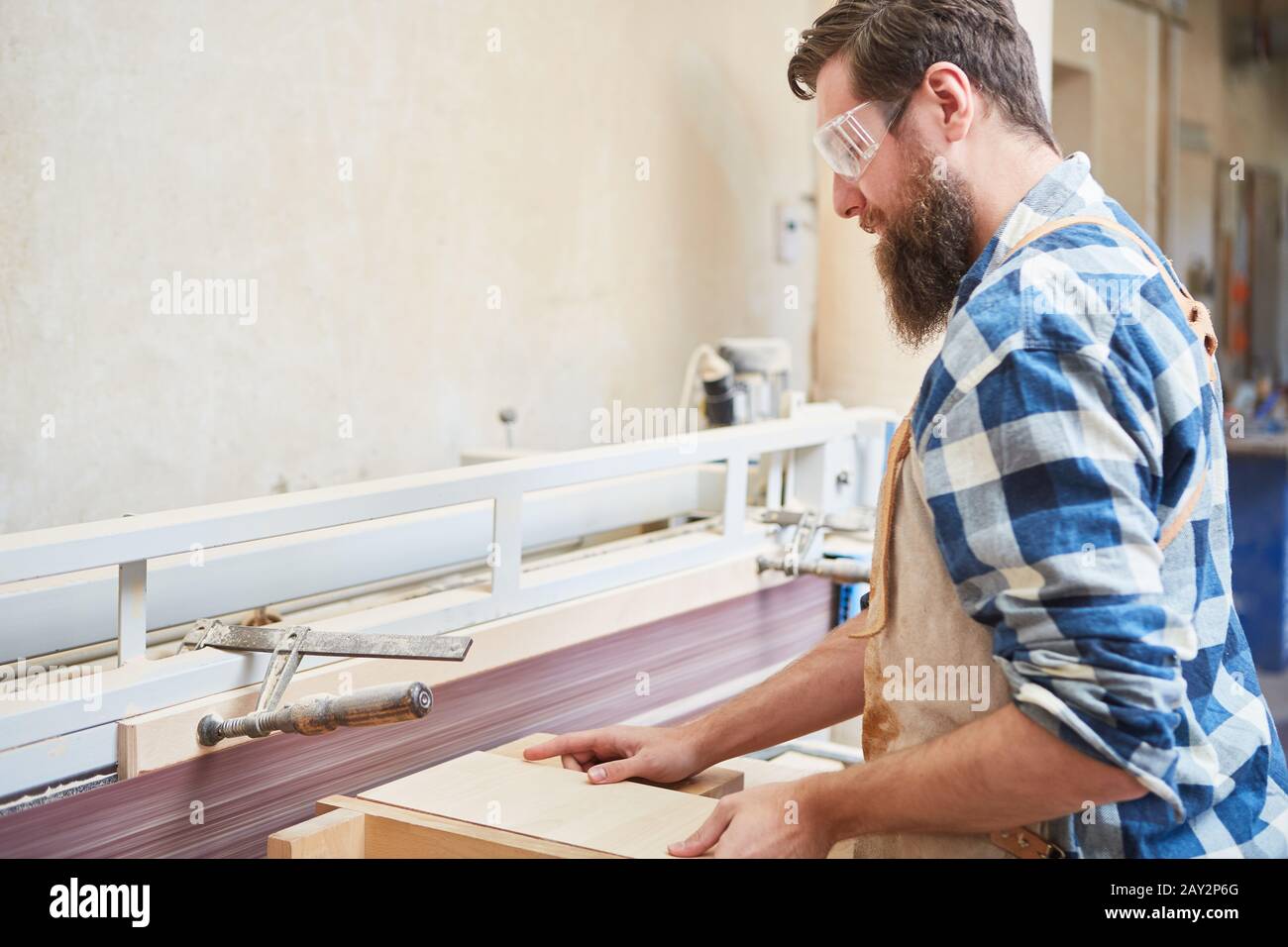Carpenter with safety glasses when sanding wood on the grinding machine Stock Photo