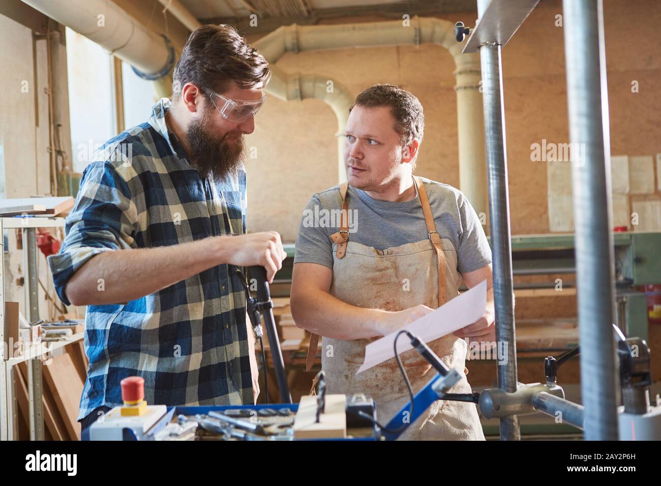 Carpenter apprentice discusses a carpentry job on paper with instructor Stock Photo