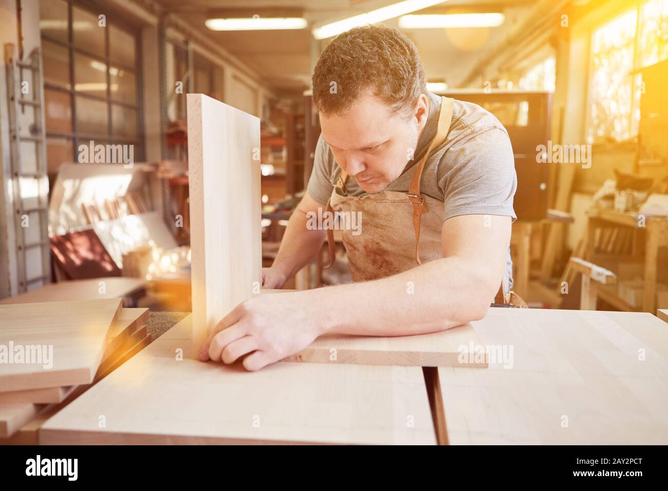 Trainee from carpenter taping wood for a shelf in furniture construction Stock Photo