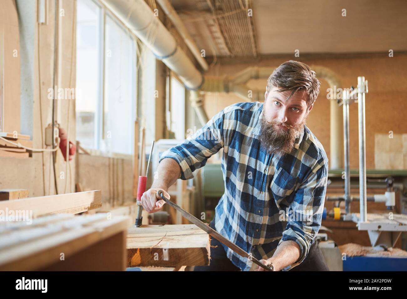 Hipster carpenters debarking wood with the pull knife in the joinery Stock Photo