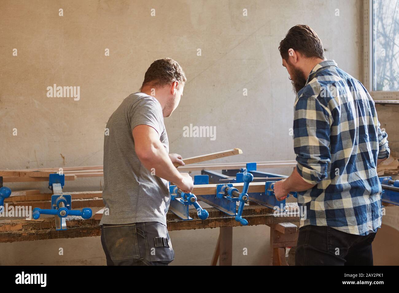 Carpenter team works together on the vice in the furniture workshop Stock Photo