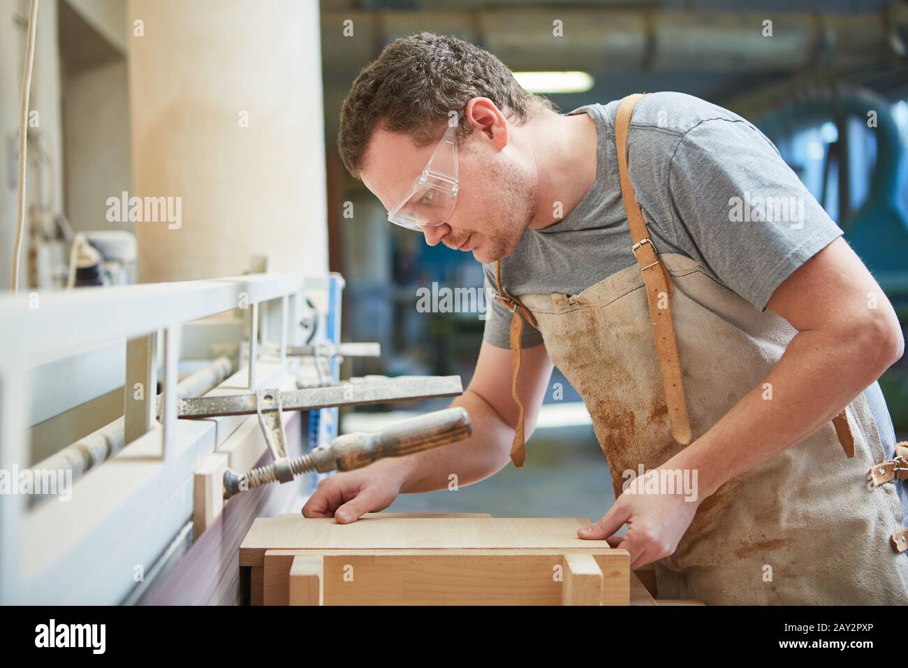 Carpenter in training cuts wood board with the table saw in the carpentry shop Stock Photo