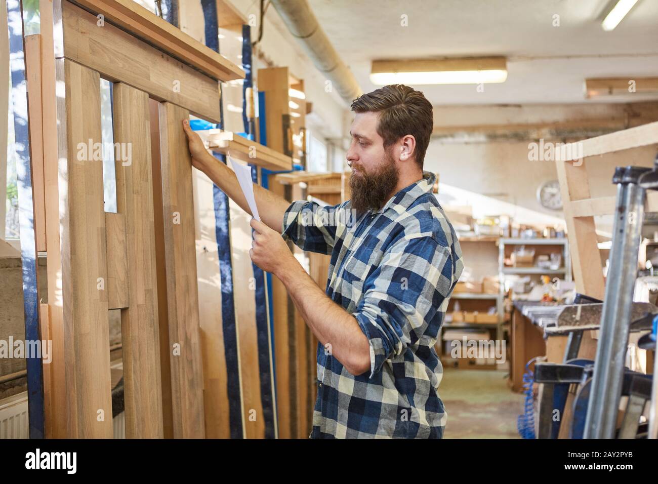 Carpenter as a furniture maker checks the checklist for an order in the joinery Stock Photo