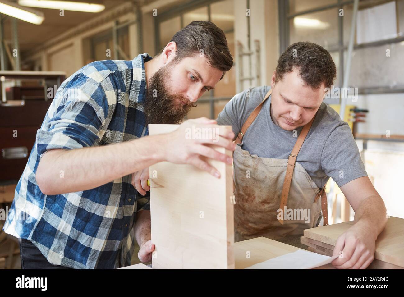 Two carpenters as furniture makers in the joinery build a wooden shelf Stock Photo