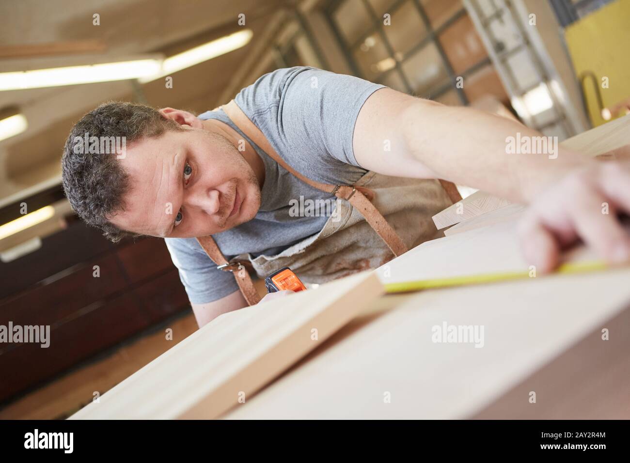 Furniture maker in training for measuring the construction of a wooden shelf Stock Photo